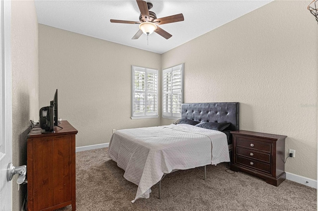 carpeted bedroom featuring a textured wall, baseboards, and ceiling fan