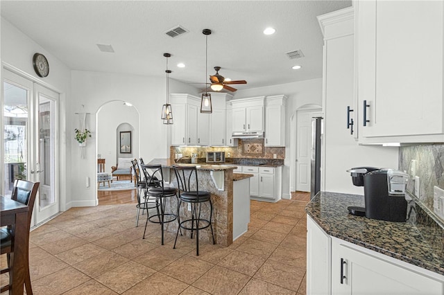 kitchen featuring light tile patterned flooring, tasteful backsplash, pendant lighting, ceiling fan, and white cabinets