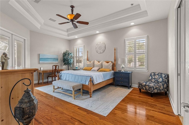 bedroom featuring multiple windows, a tray ceiling, and ceiling fan