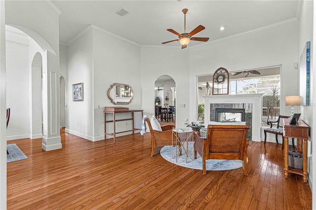 living room featuring crown molding, a high end fireplace, ceiling fan, and a high ceiling