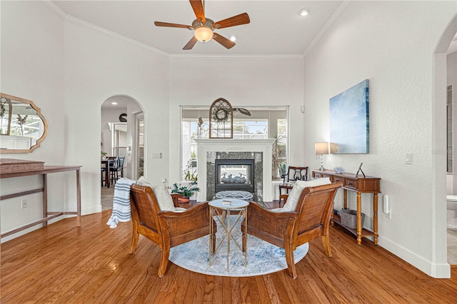 living room featuring a premium fireplace, ornamental molding, and light hardwood / wood-style floors