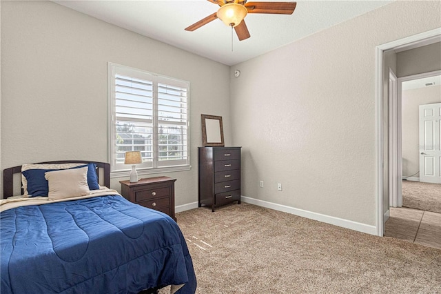 carpeted bedroom with a textured wall, baseboards, and ceiling fan