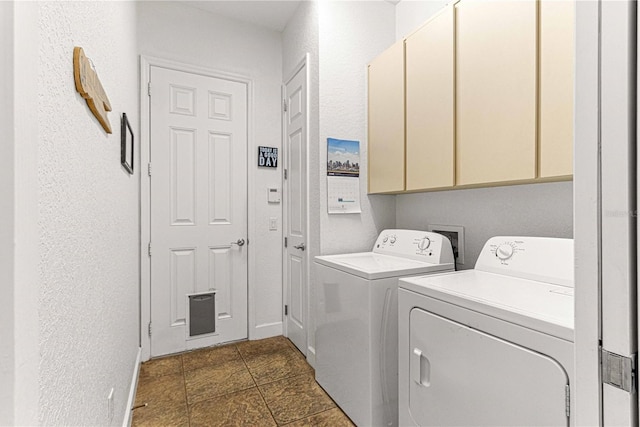 washroom with stone finish flooring, cabinet space, a textured wall, and washer and clothes dryer