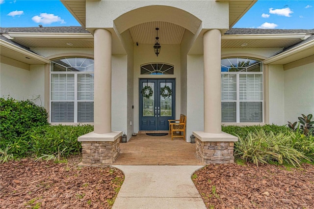 property entrance featuring french doors, roof with shingles, and stucco siding