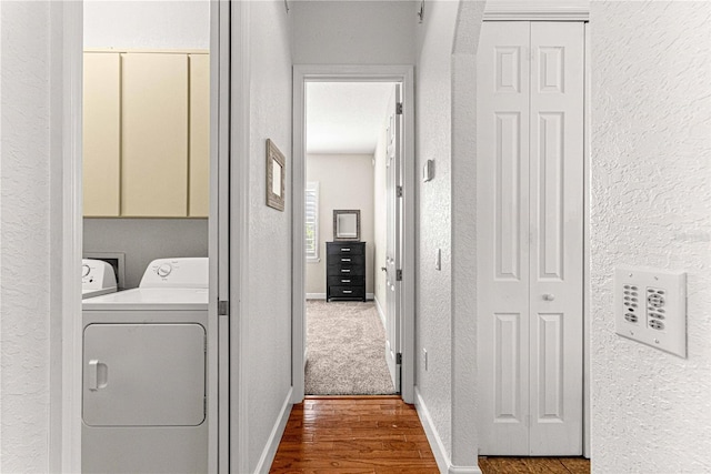 laundry area featuring baseboards, a textured wall, wood finished floors, cabinet space, and independent washer and dryer