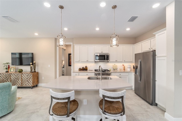 kitchen with decorative light fixtures, sink, white cabinetry, and appliances with stainless steel finishes