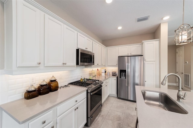 kitchen with appliances with stainless steel finishes, decorative backsplash, decorative light fixtures, white cabinets, and sink