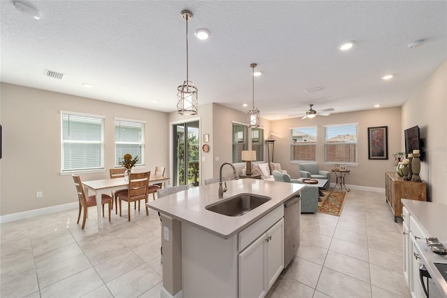 kitchen featuring a center island with sink, decorative light fixtures, dishwasher, white cabinets, and sink