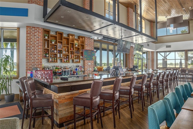 bar with hardwood / wood-style floors, a high ceiling, and tasteful backsplash