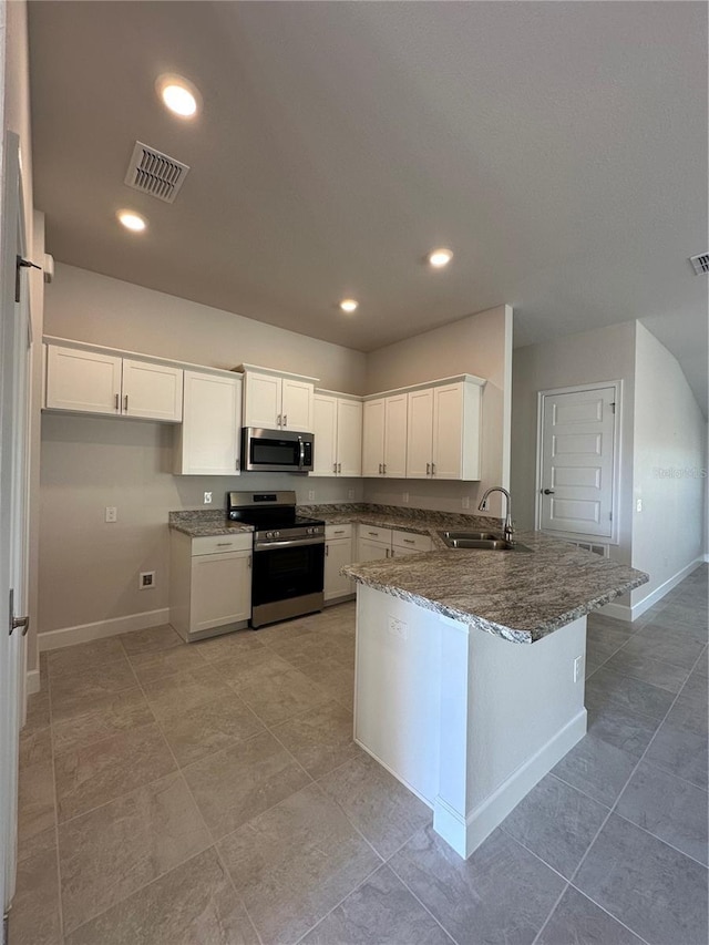 kitchen featuring dark stone counters, kitchen peninsula, sink, appliances with stainless steel finishes, and white cabinetry