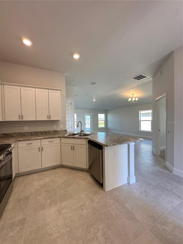 kitchen featuring kitchen peninsula, appliances with stainless steel finishes, sink, stone countertops, and white cabinetry