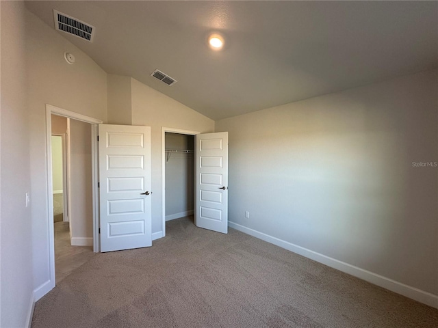 unfurnished bedroom featuring light carpet, a closet, and vaulted ceiling