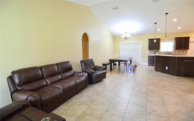 living room with light tile patterned flooring, lofted ceiling, sink, and a chandelier