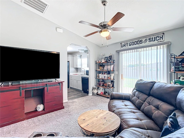 carpeted living room with lofted ceiling, sink, and ceiling fan