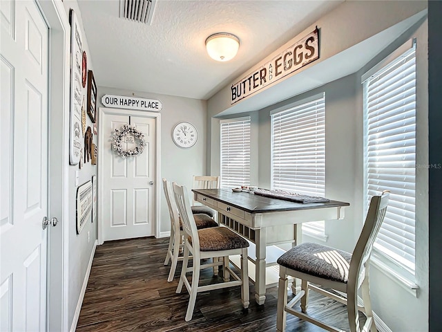 dining room with dark hardwood / wood-style floors and a textured ceiling