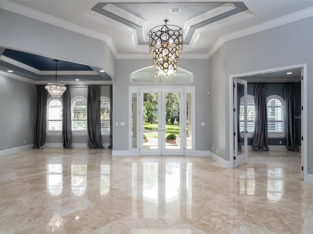 entrance foyer with ornamental molding, a raised ceiling, and a notable chandelier