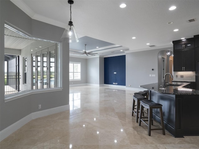 kitchen with dark stone countertops, sink, hanging light fixtures, ornamental molding, and ceiling fan