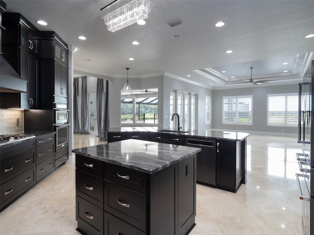 kitchen with ceiling fan with notable chandelier, a center island, stainless steel appliances, dark stone countertops, and ornamental molding