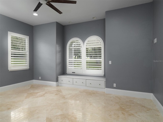 empty room featuring ceiling fan and plenty of natural light