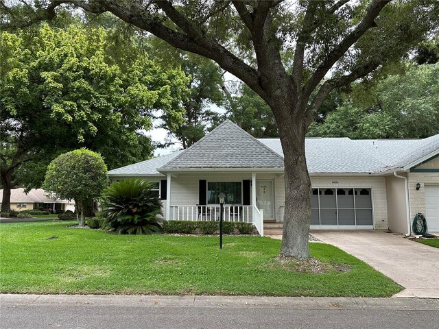 ranch-style house with covered porch, a garage, and a front lawn