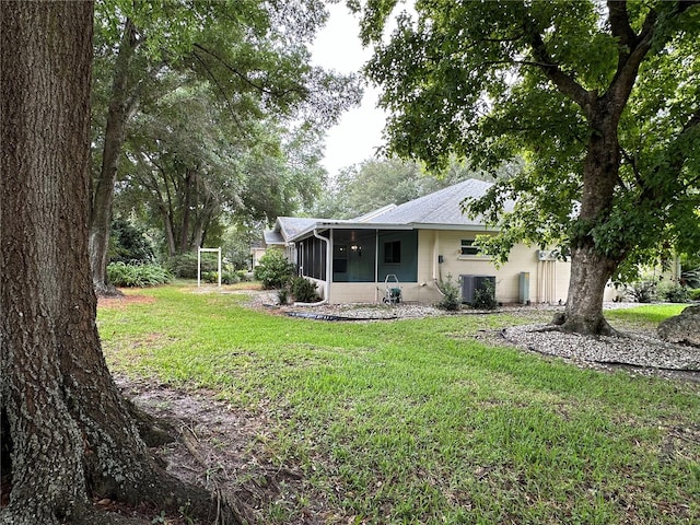 back of property featuring a sunroom, central AC, and a yard