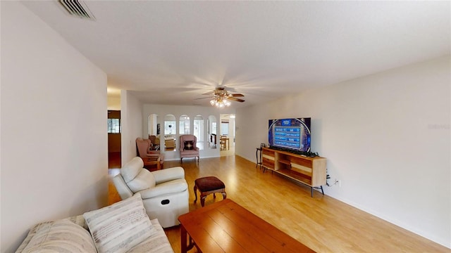 living area featuring light wood finished floors, baseboards, visible vents, and ceiling fan