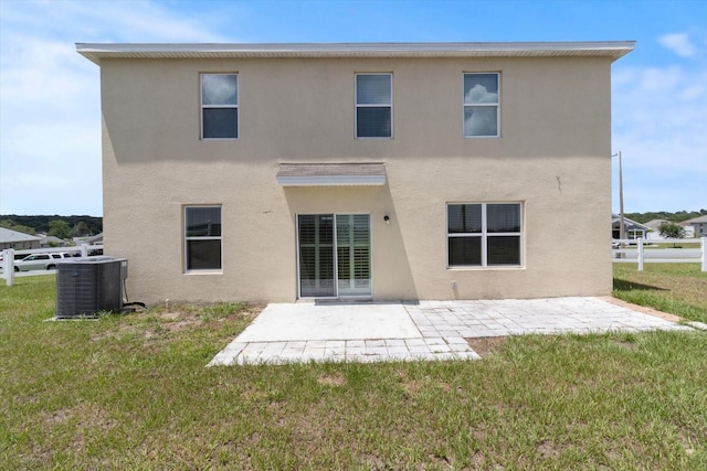 rear view of house featuring a lawn, central AC, and a patio