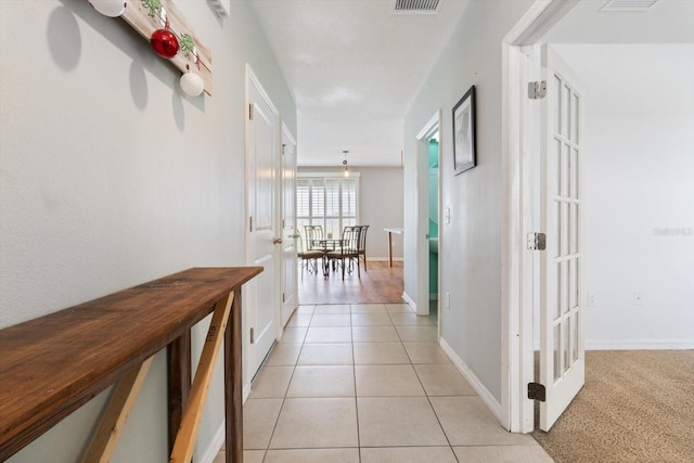 hallway featuring light tile patterned flooring and french doors