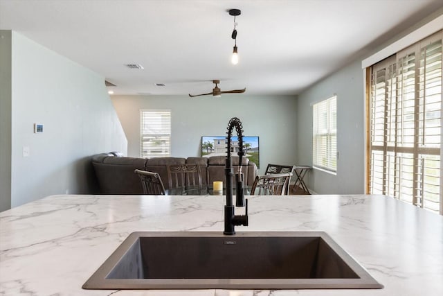 kitchen with ceiling fan, sink, and light stone counters