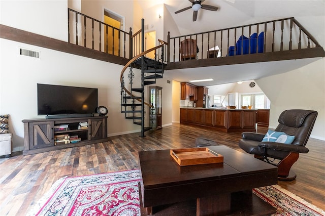 living room with a towering ceiling, hardwood / wood-style flooring, and ceiling fan