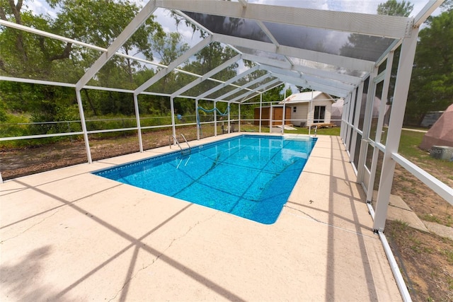 view of pool with an outdoor structure, glass enclosure, and a patio area