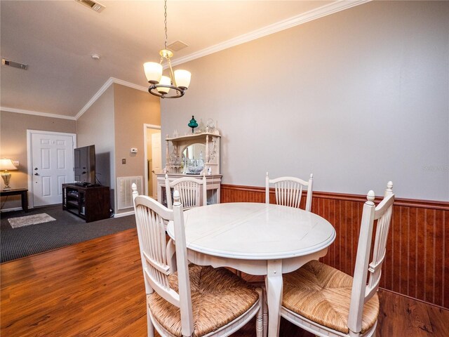 dining space featuring crown molding, an inviting chandelier, and dark carpet