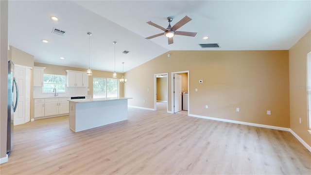 kitchen with lofted ceiling, ceiling fan, a center island, white cabinets, and decorative light fixtures