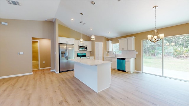 kitchen featuring hanging light fixtures, appliances with stainless steel finishes, a kitchen island, a wealth of natural light, and white cabinets