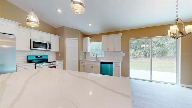 kitchen with white cabinetry, sink, hanging light fixtures, light stone counters, and stainless steel appliances