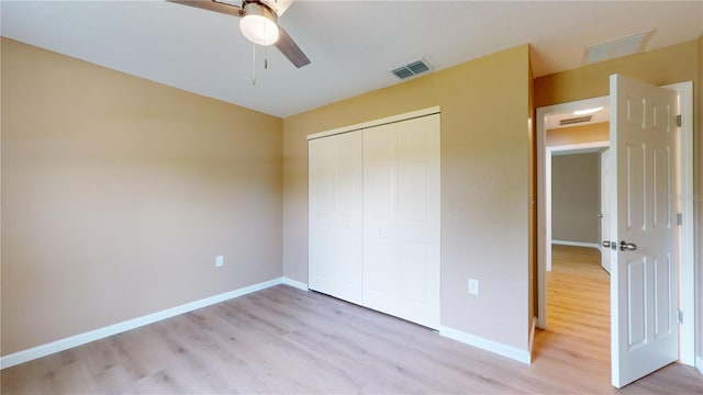 unfurnished bedroom featuring ceiling fan, a closet, and light wood-type flooring