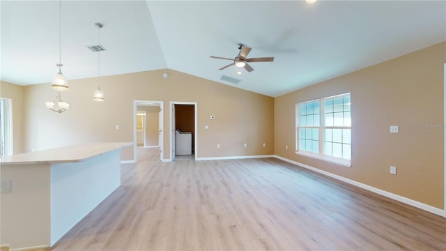 unfurnished living room featuring lofted ceiling, washer / dryer, ceiling fan with notable chandelier, and light wood-type flooring