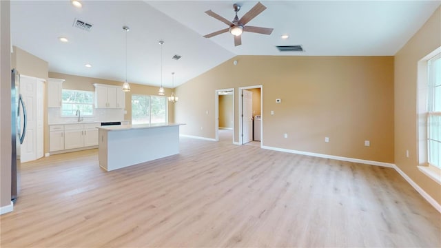 kitchen featuring ceiling fan, a center island, white cabinets, decorative light fixtures, and vaulted ceiling