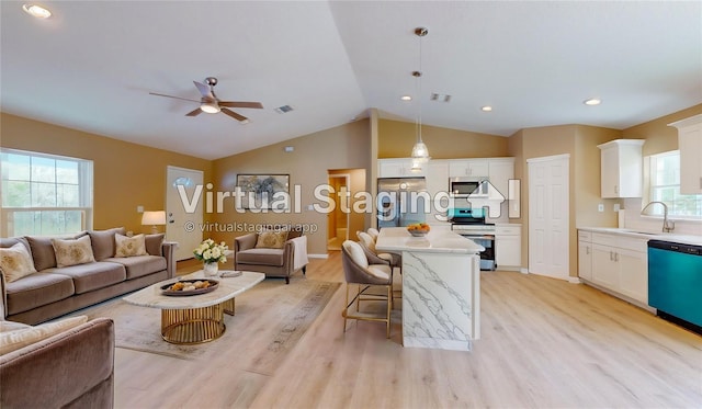 living room with vaulted ceiling, light hardwood / wood-style floors, and sink