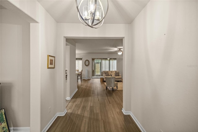 hallway with dark wood-type flooring and a chandelier