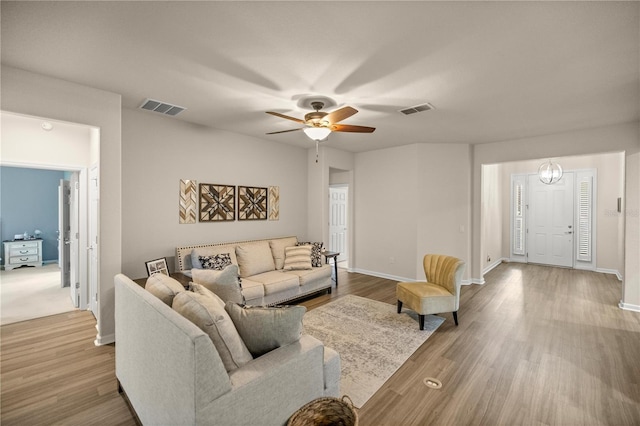 living room featuring ceiling fan with notable chandelier and hardwood / wood-style floors