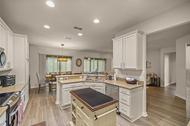 kitchen featuring kitchen peninsula, stainless steel appliances, white cabinets, and sink