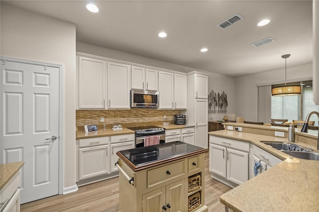 kitchen with appliances with stainless steel finishes, a center island, white cabinetry, sink, and backsplash