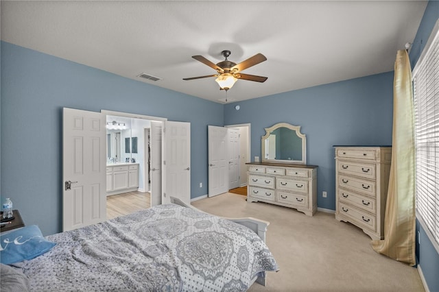 bedroom featuring ceiling fan, light colored carpet, and connected bathroom