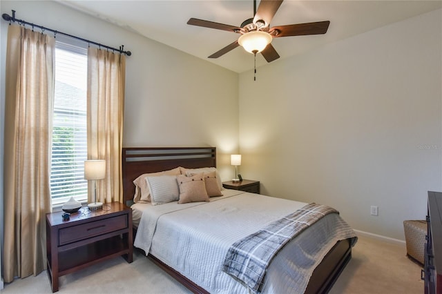 bedroom with ceiling fan, light colored carpet, and multiple windows