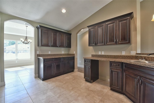 kitchen with dark brown cabinetry, vaulted ceiling, sink, decorative light fixtures, and an inviting chandelier