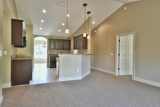 kitchen featuring light stone counters, pendant lighting, light colored carpet, lofted ceiling, and dark brown cabinets