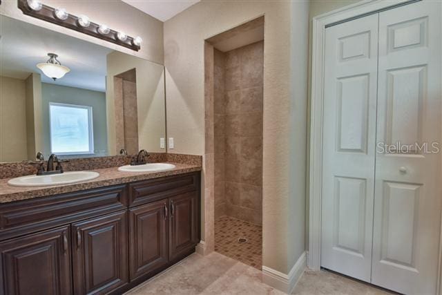 bathroom featuring a tile shower, vanity, and tile patterned floors