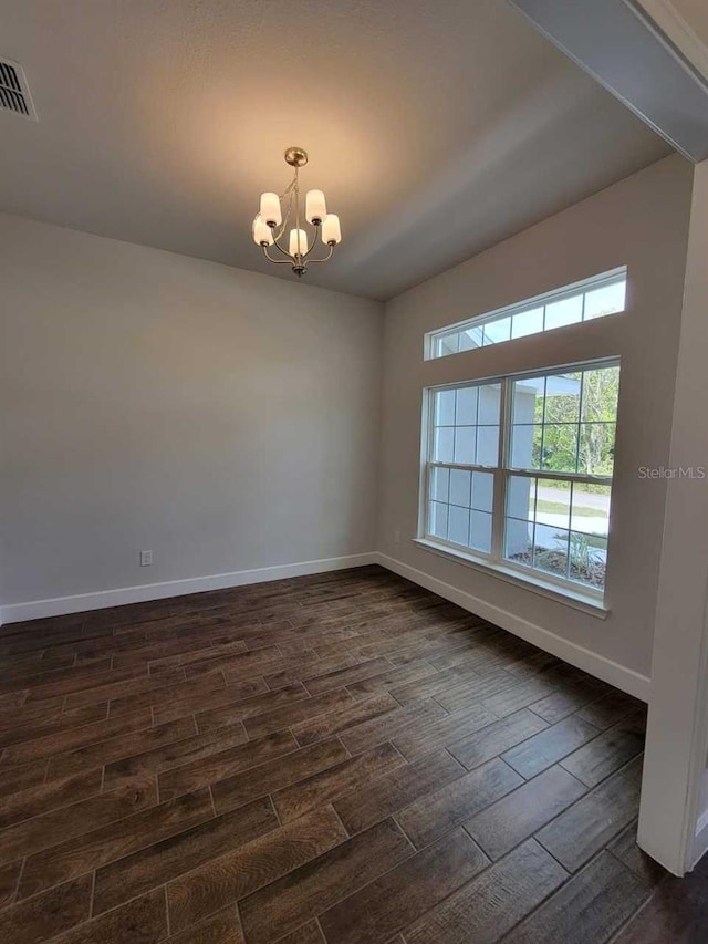 unfurnished room featuring dark hardwood / wood-style flooring and an inviting chandelier