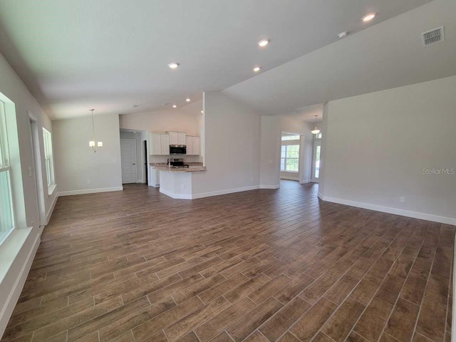 unfurnished living room featuring dark wood-type flooring, lofted ceiling, and an inviting chandelier